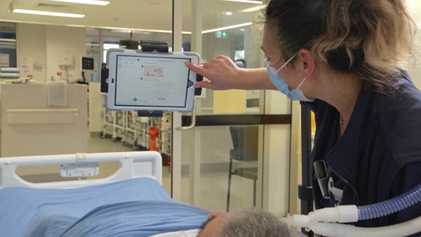 A nurse touches the device screen to start the virtual visit