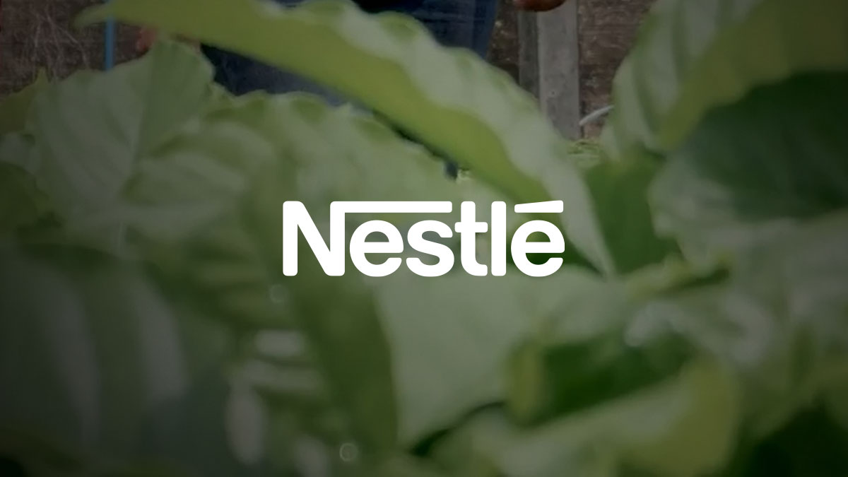 Nestlé logo centered over blurred green leaves.